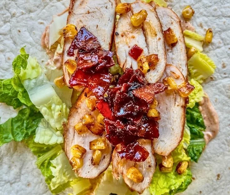 Bacon Jam Chicken Caesar Salad Wraps on a plate garnished with fresh vegetables