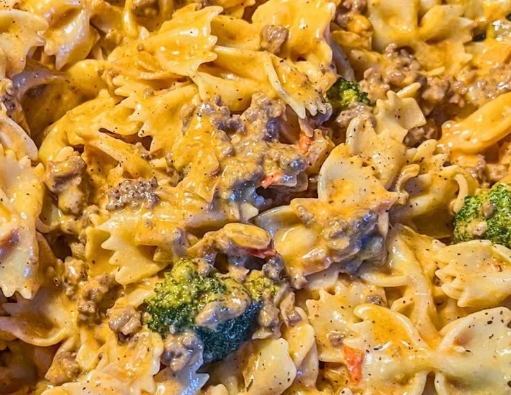 Creamy tomato beef pasta with herbs and cheese, served in a bowl
