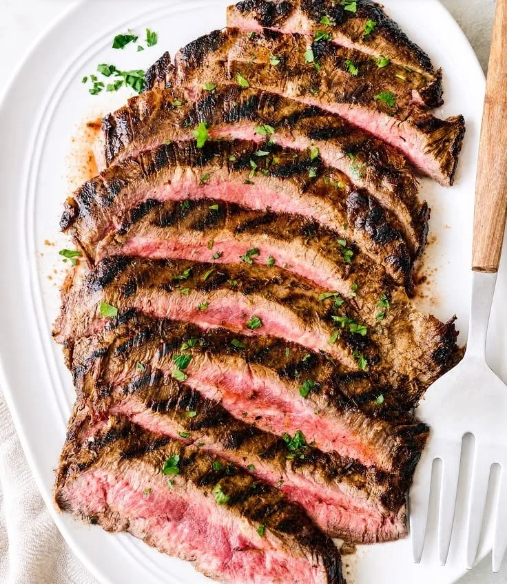 Delicious grilled flank steak with herbs and spices on a plate.