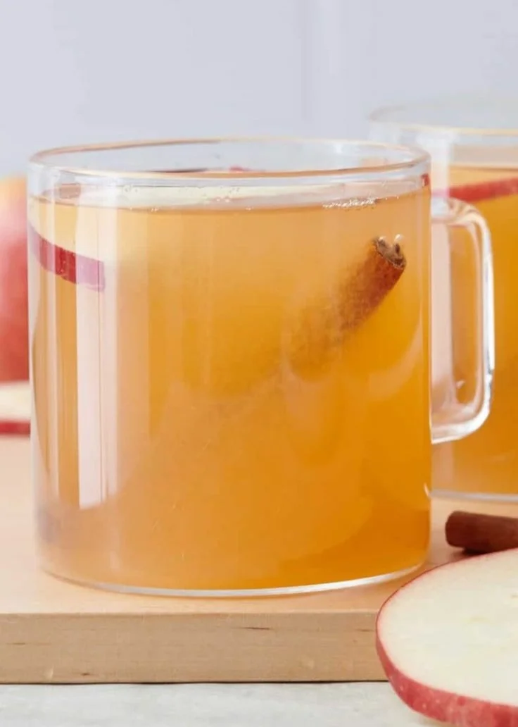 Homemade apple cider preparation with fresh apples and equipment.