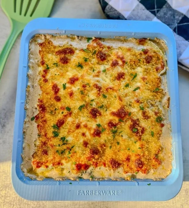 Philly Cheesesteak casserole dish topped with melted cheese and fresh herbs