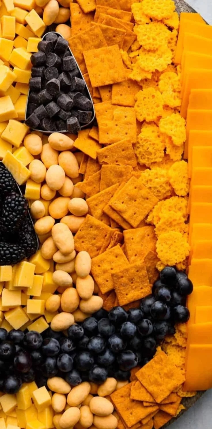 Colorful pumpkin charcuterie board filled with seasonal snacks and decorations.