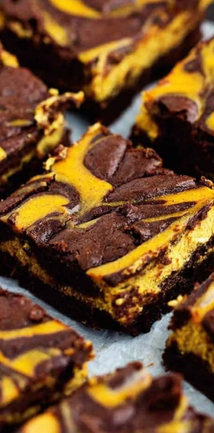 Delicious Pumpkin Cheesecake Brownies topped with creamy cheesecake swirl