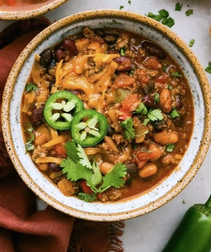 Bowl of Pumpkin Chili topped with herbs and served with crusty bread