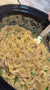 Bowl of Slow Cooker Golden Beef and Noodles garnished with herbs